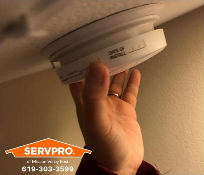 A person tests a smoke detector.