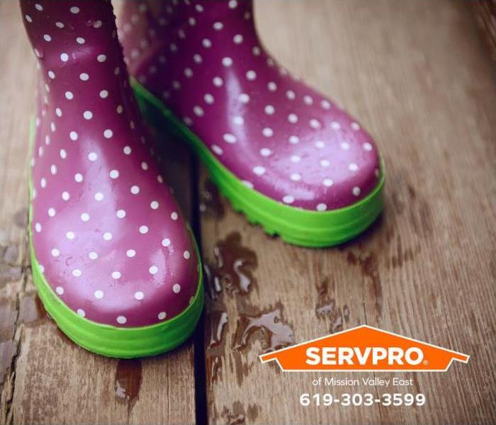 A pair of rubber boots dry off on a wooded deck.