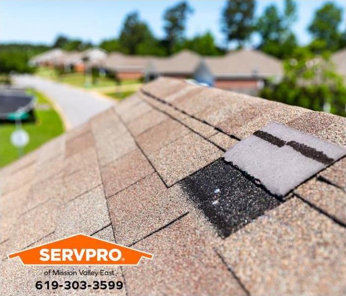 A roof is shown with a wind-damaged shingle.