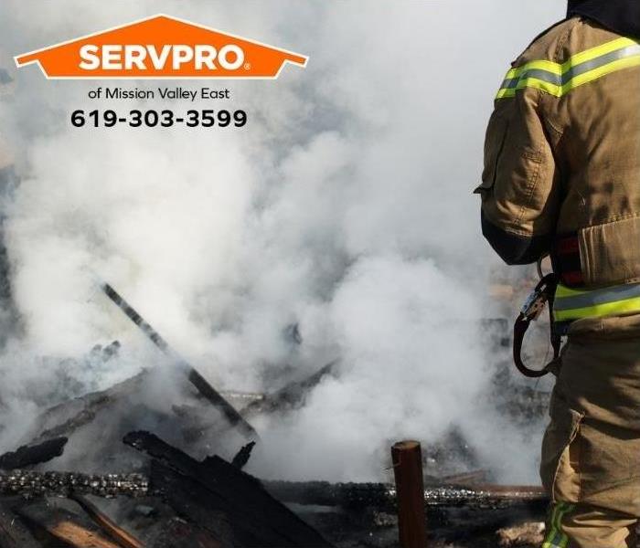 A firefighter is surrounded by smoke while putting out a fire. 