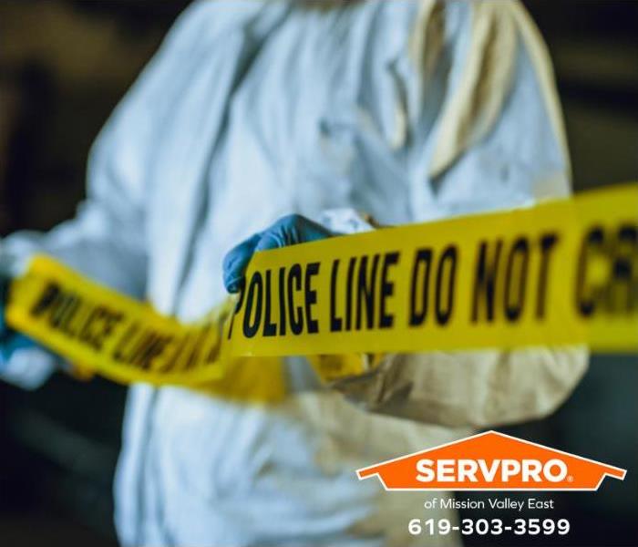 A crime scene technician places yellow crime scene tape around the perimeter of an active investigation. 