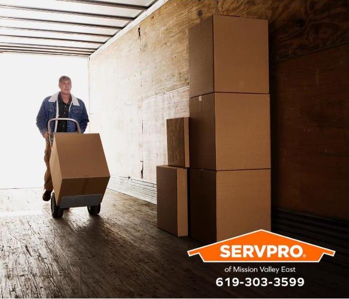 Boxes and household furniture are loaded in a moving truck.